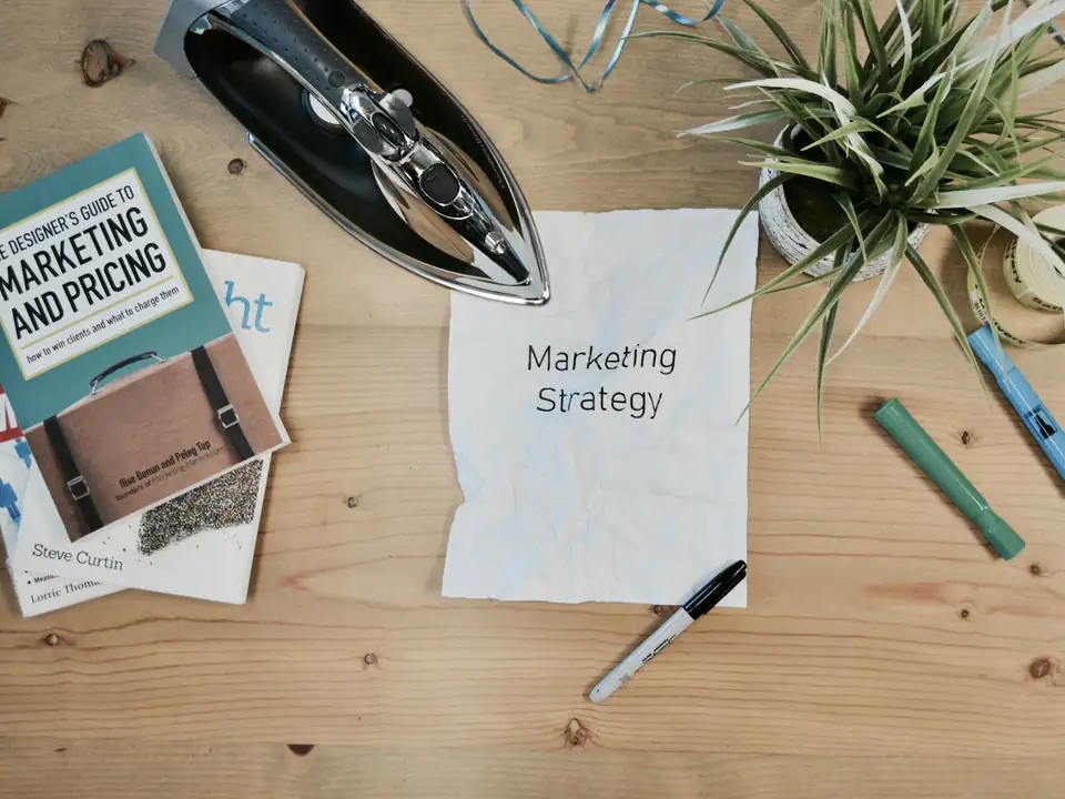 Mesa de trabajo vista desde arriba con una nota de estrategia, un libro y material de oficina